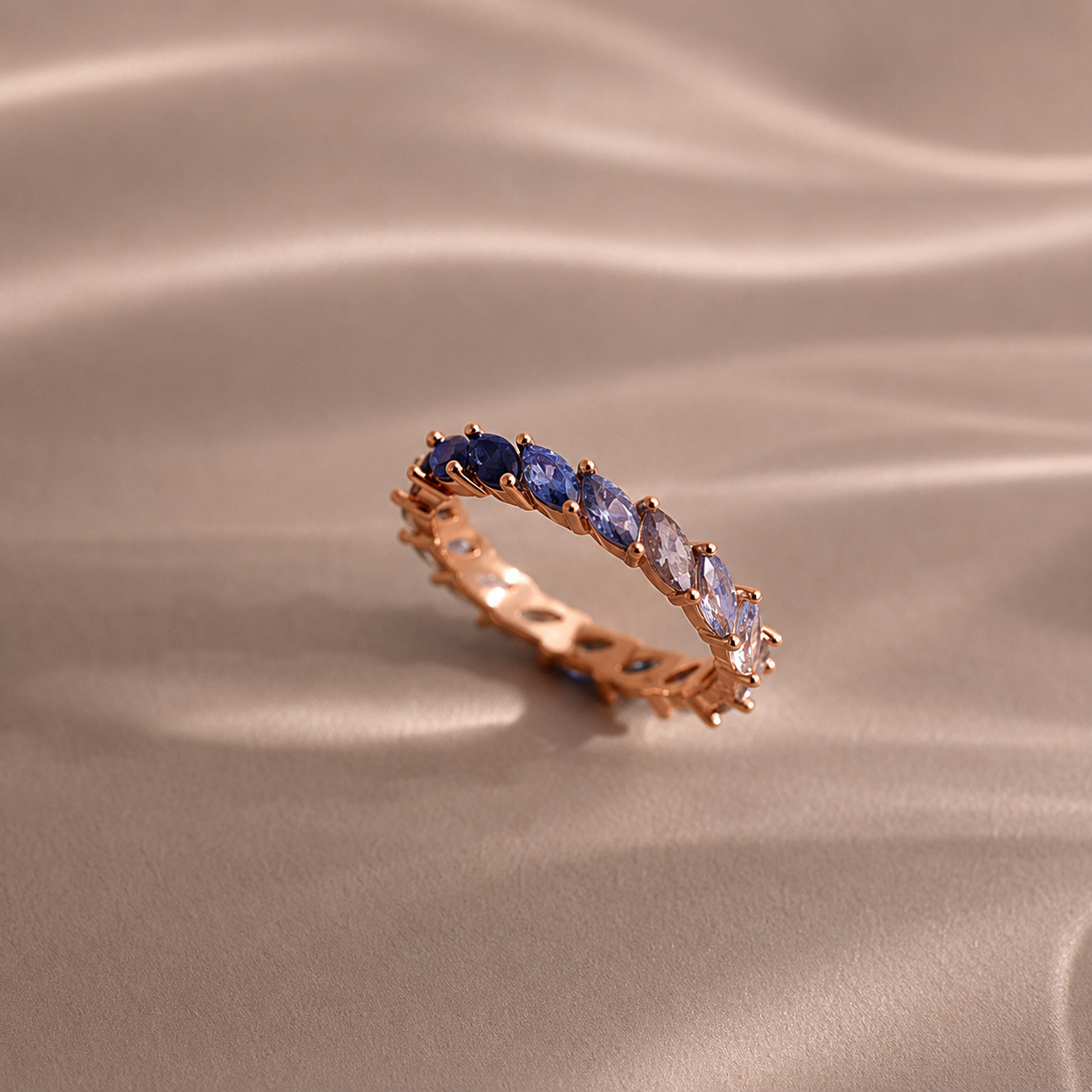 Rose gold ring with blue gemstones on a beige fabric background